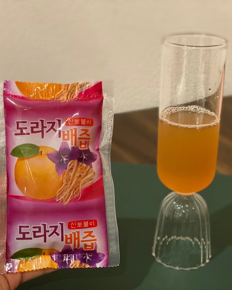 Korean bellflower-pear extract pouch beside a glass of warm amber juice