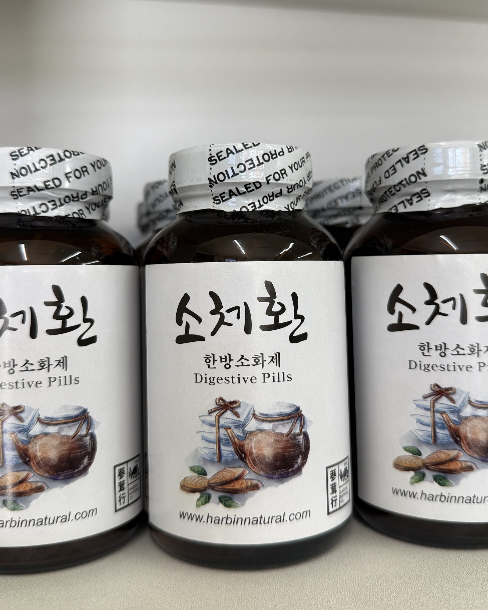 Three Sochehwan digestive pill bottles in a row on the herb cabinet backdrop